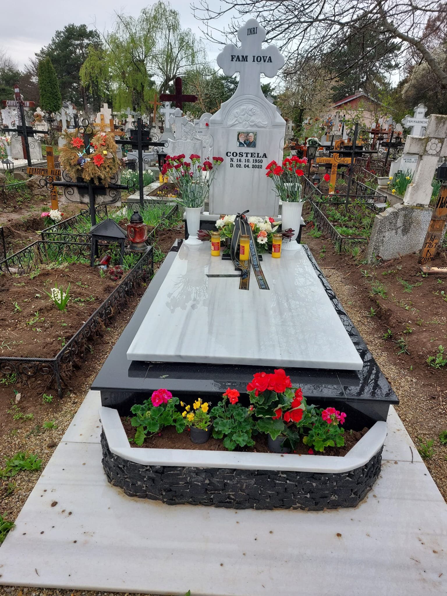 Monument din marmură albă cu cruce sculptată și bordură din granit negru